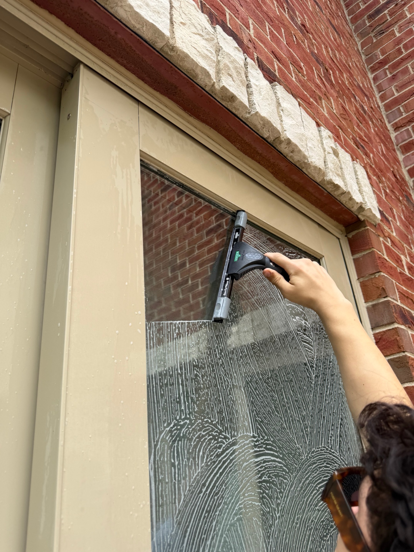 Close-up squeegee pass on a soapy first-floor window
